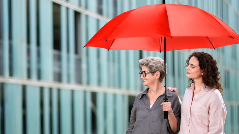 Zwei Damen unter einem roten Schirm