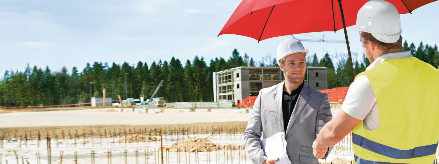 Zwei Männer mit Helmen unterhalten sich unter dem roten Schutzschirm