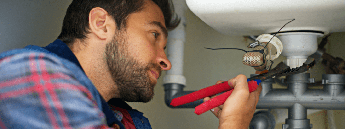 Ein Handwerker schraubt an einem Waschbecken