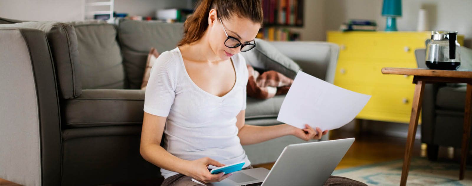 Frau sitzt im Wohnzimmer vor dem Laptop 